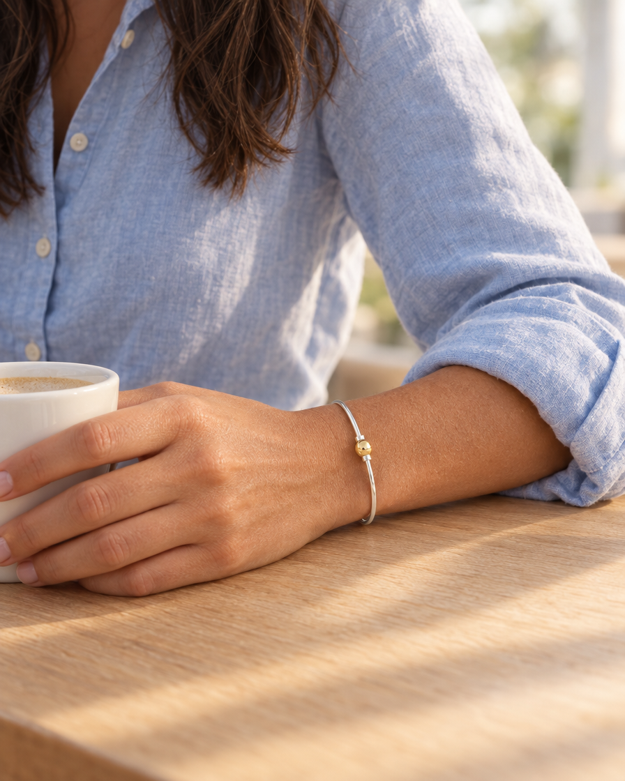 Coastal Ball Bracelet worn, hand resting on a coffee cup
